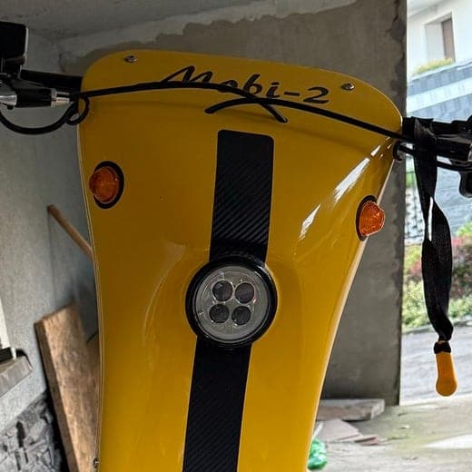 Zbliżenie na okrągły reflektor LED Mobi-2 i pomarańczowe kierunkowskazy w kształcie łzy.